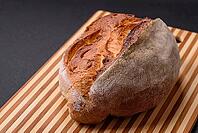 Food, A loaf of brown bread with grains of cereals on a wooden cutting board on a dark concrete background [IBR124773754]
