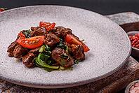 Food, Delicious warm salad with pieces of meat, spinach, tomatoes, salt, spices and herbs on a dark concrete background [IBR124773761]