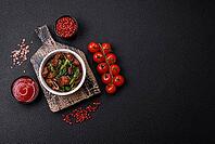 Food, Delicious warm salad with pieces of meat, spinach, tomatoes, salt, spices and herbs on a dark concrete background [IBR124773764]