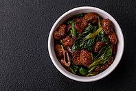 Food, Delicious warm salad with pieces of meat, spinach, tomatoes, salt, spices and herbs on a dark concrete background [IBR124773765]