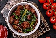 Food, Delicious warm salad with pieces of meat, spinach, tomatoes, salt, spices and herbs on a dark concrete background [IBR124773766]