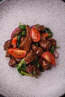 Food, Delicious warm salad with pieces of meat, spinach, tomatoes, salt, spices and herbs on a dark concrete background [IBR124773768]
