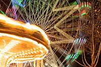 Colourful striped light illuminated spinning ferris wheel in motion moving at night [IBR124817843]