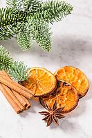 Slices of dried orange and a branch of pine on marble surface [IBR124817844]