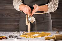 Female hands preparing Christmas cookies. Raw dough and cookie cutters on marble kitchen tabletop [IBR124817845]