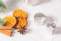 Slices of dried orange and a branch of pine Christmas cookies cutters on marble surface [IBR124817847]