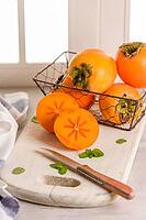 Delicious fresh persimmon fruit on kitchen countertop [IBR124817877]