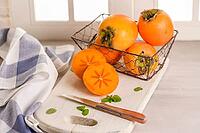 Delicious fresh persimmon fruit on kitchen countertop [IBR124817880]