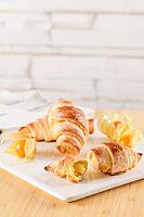 Small croissant with physalis fruits in white ceramic tray, homemade cakes on wooden table top [IBR124817887]