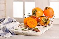 Delicious fresh persimmon fruit on kitchen countertop [IBR124817888]