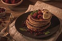 Pancakes with raspberries, banana slices, pomegranate seeds and honey on wooden vintage table [IBR124817902]