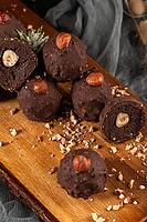 Dark chocolate truffles with hazelnuts over wooden cutting board [IBR124817913]