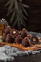 Dark chocolate truffles with hazelnuts over wooden cutting board [IBR124817914]
