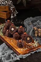Dark chocolate truffles with hazelnuts over wooden cutting board [IBR124817917]