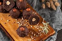 Dark chocolate truffles with hazelnuts over wooden cutting board [IBR124817920]