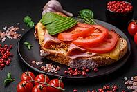 Food, Delicious nutritious grilled toast with ham, cheese, tomatoes and avocado with salt, spices and herbs on a dark concrete background [IBR124842036]
