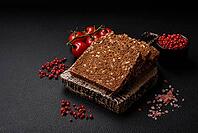 Food, Delicious fresh crispy brown bread with seeds and grains cut into slices on a dark concrete background [IBR124842059]