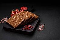 Food, Delicious fresh crispy brown bread with seeds and grains cut into slices on a dark concrete background [IBR124842060]