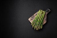 Food, Delicious fresh sprigs of asparagus on a dark textured background. Ingredients for a healthy vegetarian meal [IBR124842061]