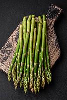 Food, Delicious fresh sprigs of asparagus on a dark textured background. Ingredients for a healthy vegetarian meal [IBR124842062]