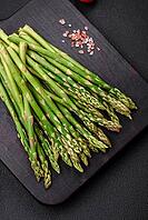 Food, Delicious fresh sprigs of asparagus on a dark textured background. Ingredients for a healthy vegetarian meal [IBR124842063]