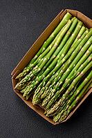 Food, Delicious fresh sprigs of asparagus on a dark textured background. Ingredients for a healthy vegetarian meal [IBR124842064]