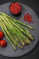 Food, Delicious fresh sprigs of asparagus on a dark textured background. Ingredients for a healthy vegetarian meal [IBR124842065]