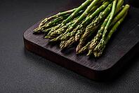 Food, Delicious fresh sprigs of asparagus on a dark textured background. Ingredients for a healthy vegetarian meal [IBR124842067]