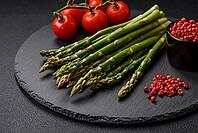 Food, Delicious fresh sprigs of asparagus on a dark textured background. Ingredients for a healthy vegetarian meal [IBR124842068]