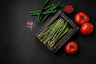 Food, Delicious fresh sprigs of asparagus on a dark textured background. Ingredients for a healthy vegetarian meal [IBR124842069]