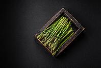 Food, Delicious fresh sprigs of asparagus on a dark textured background. Ingredients for a healthy vegetarian meal [IBR124842070]