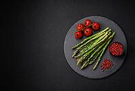 Food, Delicious fresh sprigs of asparagus on a dark textured background. Ingredients for a healthy vegetarian meal [IBR124842072]