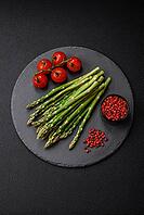 Food, Delicious fresh sprigs of asparagus on a dark textured background. Ingredients for a healthy vegetarian meal [IBR124842073]