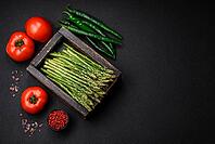 Food, Delicious fresh sprigs of asparagus on a dark textured background. Ingredients for a healthy vegetarian meal [IBR124842075]