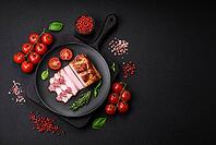Food, Delicious calorie smoked bacon with salt, spices and herbs on a dark concrete background [IBR124842081]
