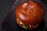 Food, Burger with juicy beef cutlet, cheese, tomatoes, salt, spices and herbs on a dark concrete background [IBR124842083]