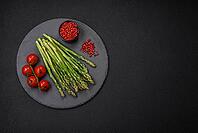 Food, Delicious fresh sprigs of asparagus on a dark textured background. Ingredients for a healthy vegetarian meal [IBR124842086]