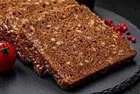Food, Delicious fresh crispy brown bread with seeds and grains cut into slices on a dark concrete background [IBR124842087]