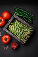 Food, Delicious fresh sprigs of asparagus on a dark textured background. Ingredients for a healthy vegetarian meal [IBR124842088]