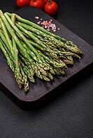 Food, Delicious fresh sprigs of asparagus on a dark textured background. Ingredients for a healthy vegetarian meal [IBR124842089]