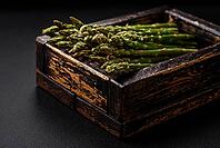 Food, Delicious fresh sprigs of asparagus on a dark textured background. Ingredients for a healthy vegetarian meal [IBR124842090]