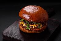 Food, Burger with juicy beef cutlet, cheese, tomatoes, salt, spices and herbs on a dark concrete background [IBR124842092]