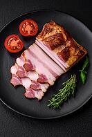 Food, Delicious calorie smoked bacon with salt, spices and herbs on a dark concrete background [IBR124842093]