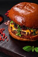 Food, Burger with juicy beef cutlet, cheese, tomatoes, salt, spices and herbs on a dark concrete background [IBR124842094]