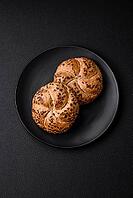 Food, Delicious freshly baked crispy bun or kaiser roll with sesame seeds on dark concrete background [IBR124842096]
