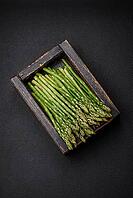 Food, Delicious fresh sprigs of asparagus on a dark textured background. Ingredients for a healthy vegetarian meal [IBR124842098]
