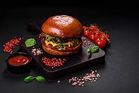 Food, Burger with juicy beef cutlet, cheese, tomatoes, salt, spices and herbs on a dark concrete background [IBR124842099]