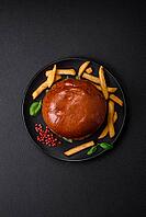 Food, Burger with juicy beef cutlet, cheese, tomatoes, salt, spices and herbs on a dark concrete background [IBR124842102]