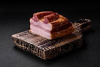 Food, Delicious calorie smoked bacon with salt, spices and herbs on a dark concrete background [IBR124842103]