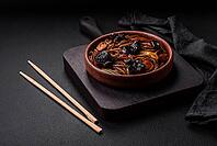 Food, Delicious fresh buckwheat noodles or udon with mushrooms, peppers and other vegetables, spices and herbs on a dark concrete background [IBR124842104]